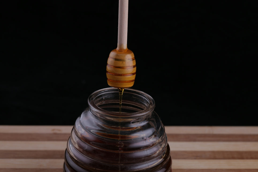 a honey dip being poured into a glass jar