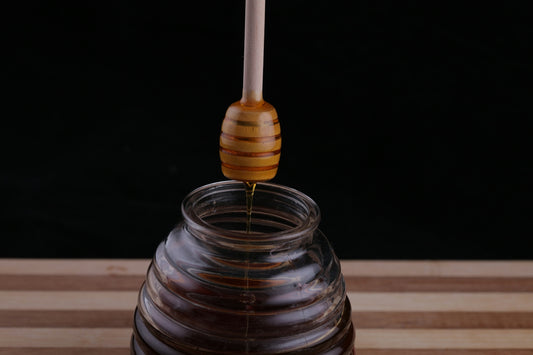a honey dip being poured into a glass jar